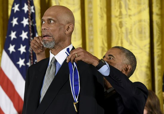 أوباما يمسك بالميدالية لتقليد كريم عبد الجبار الوسام
