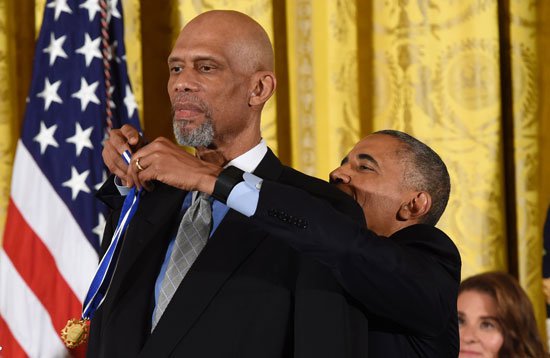 أوباما يمسك بالميدالية لتقليد كريم عبد الجبار الوسام